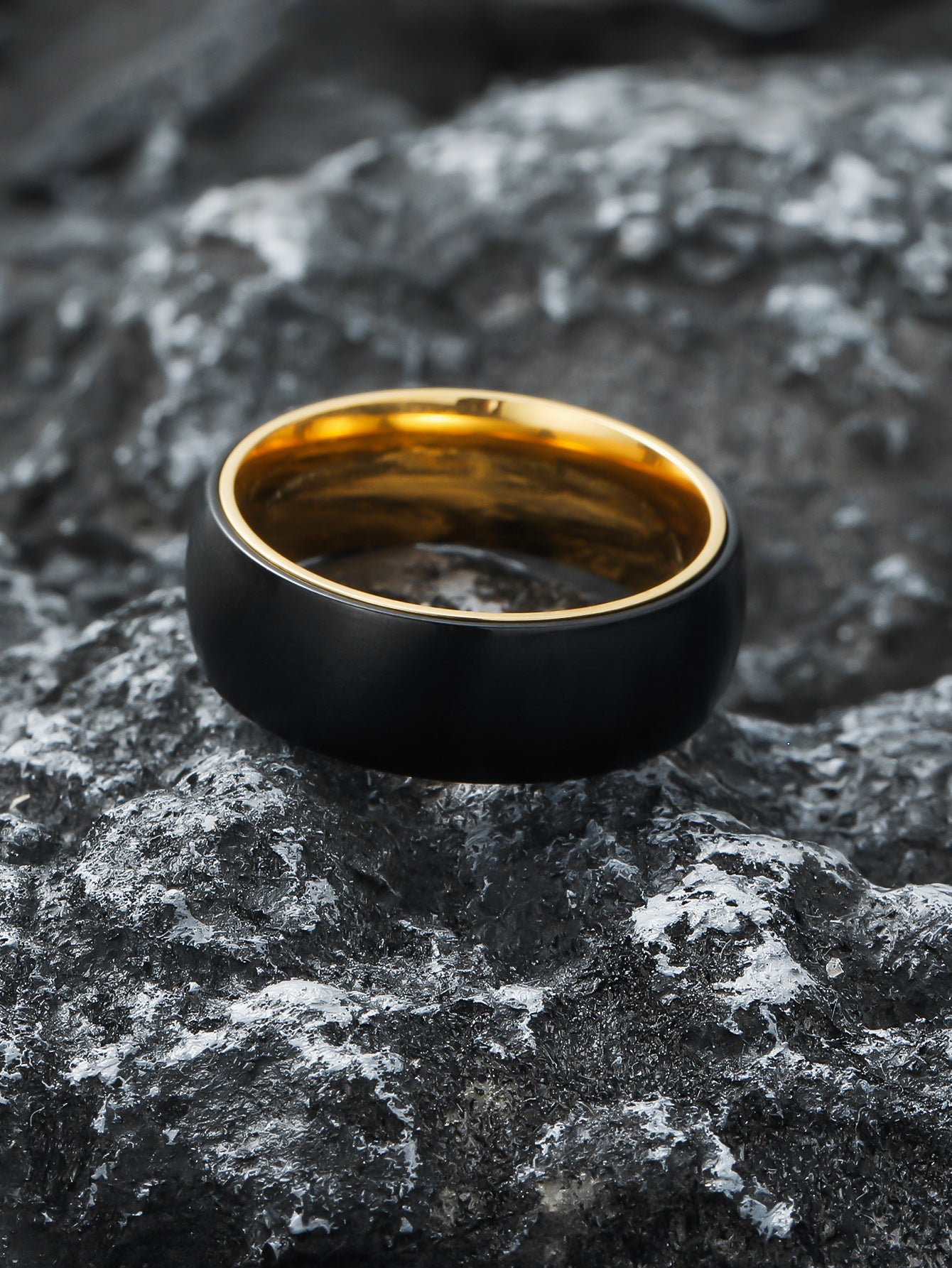 Black Gold Spinner Fidget Ring laid on natural rock surface – Calmfor stress relief jewelry
