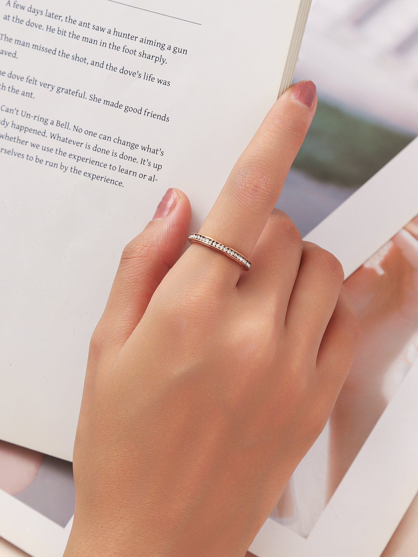 A_model_wearing_iced_out_slim_spinner_ring_is_reading_book