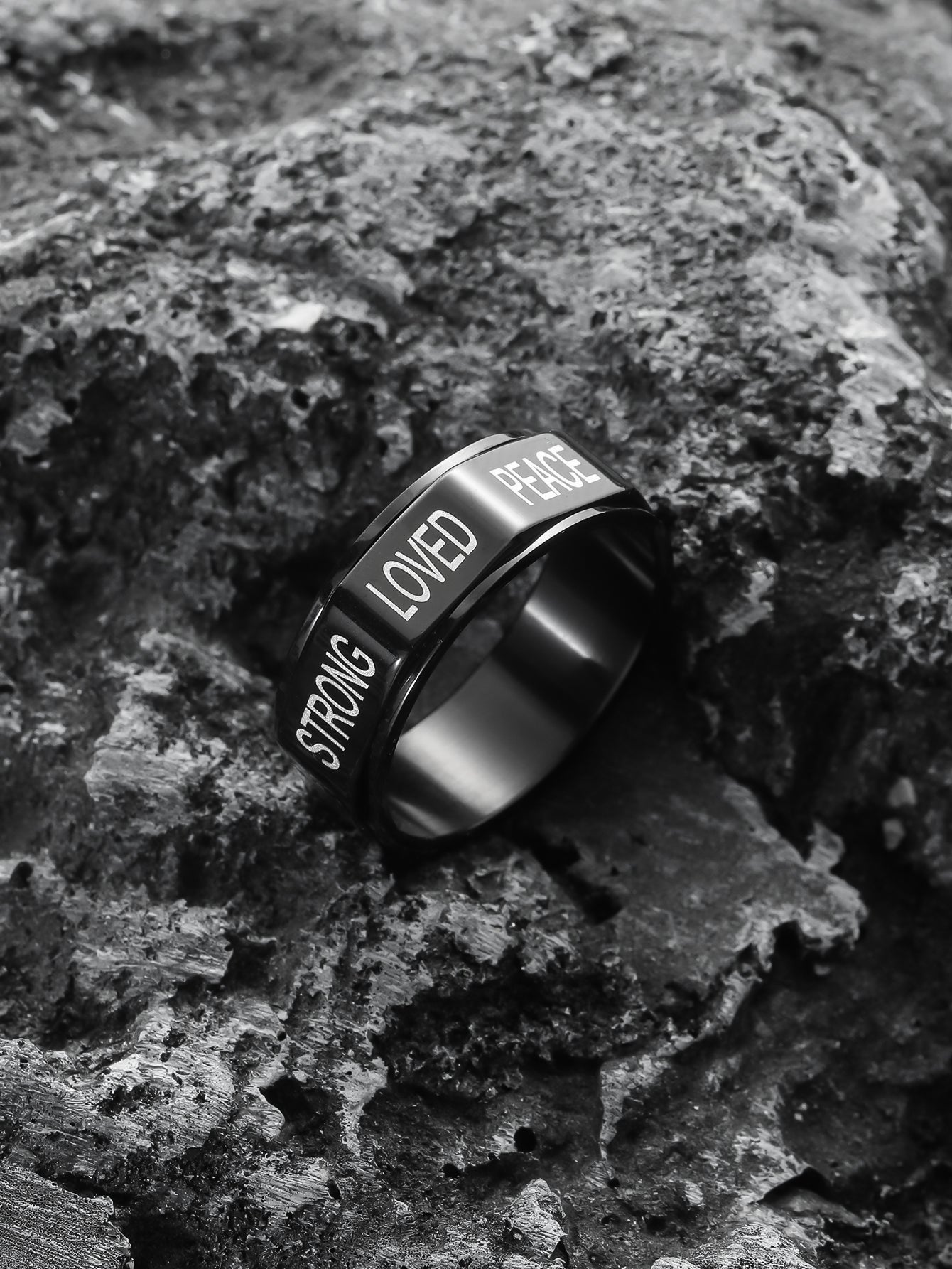 This black encourgaement spinner ring is standing on the rock