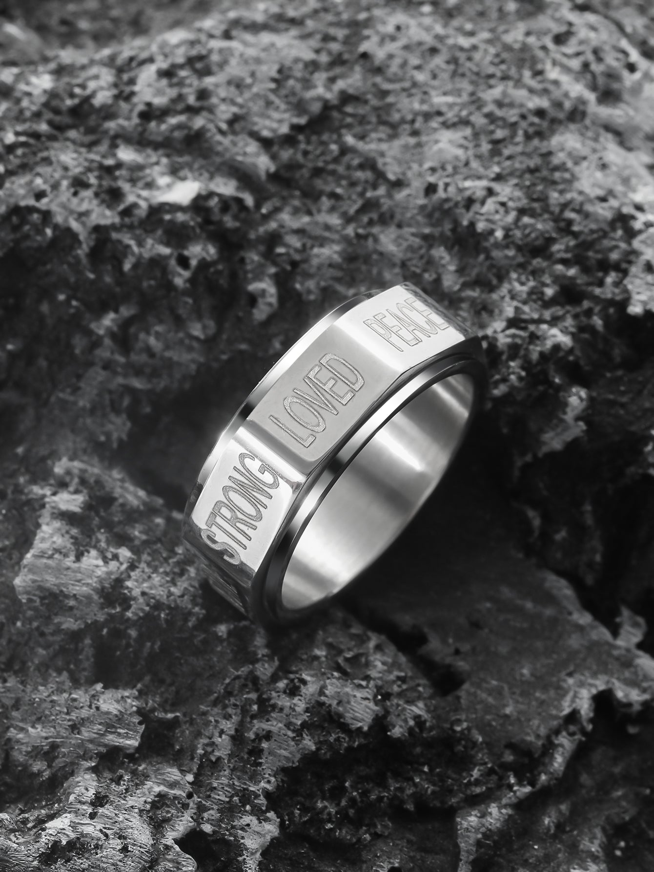 this silver positive words spinner ring is lying on the rock