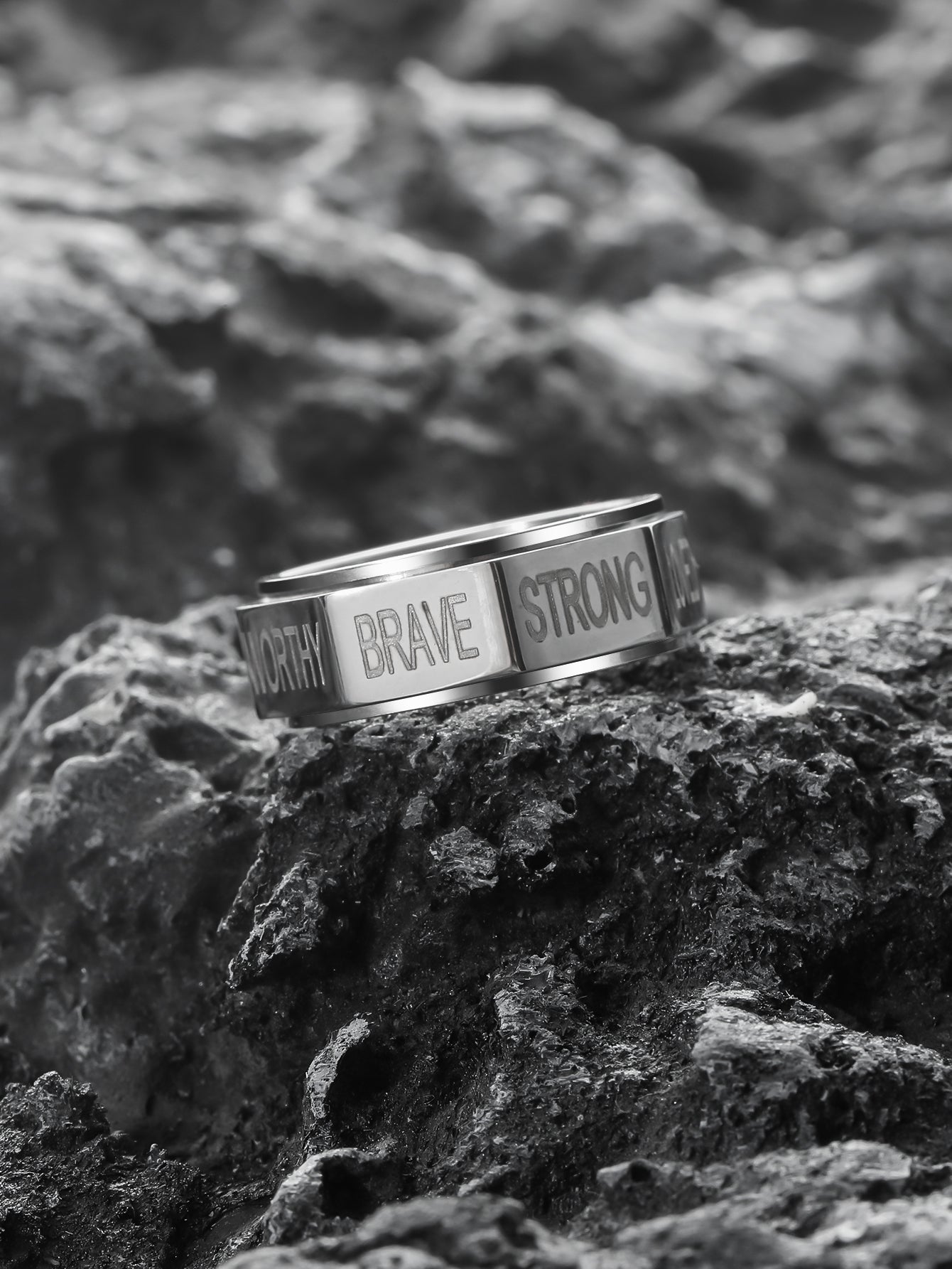 this silver positive words spinner ring is lying on the rock